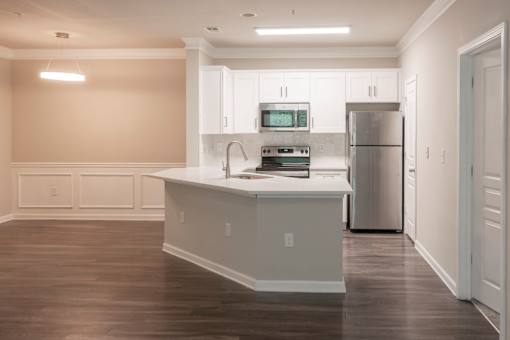 A kitchen with white cabinets and a wooden floor.