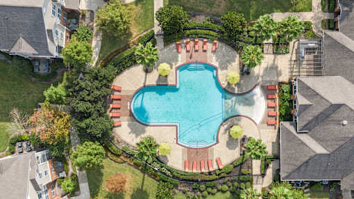 An aerial view of a swimming pool surrounded by a red fence and palm trees at The Fenwick Apartments, Humble, TX, 77396