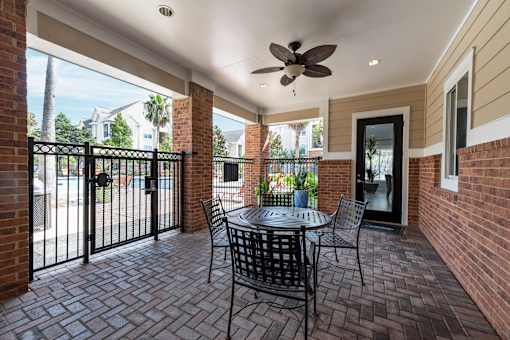 A patio with a table and chairs and a ceiling fan at The Fenwick Apartments, Texas 77396
