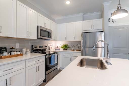 A kitchen with white cabinets and a stainless steel refrigerator.at The One at Millington, Millington, TN