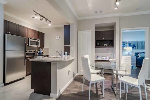 A modern kitchen with a glass table and white chairs. at The Ren, Atlanta, 30329