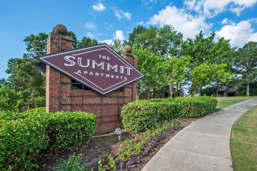 a sign that says the summit apartments with trees in the background