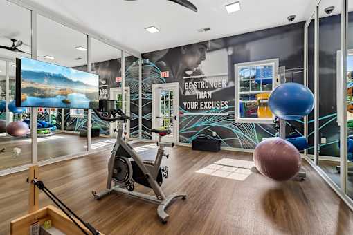 A gym with a wooden floor and a variety of exercise equipment.