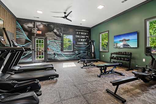 A gym with treadmills, benches, and a motivational poster on the wall.