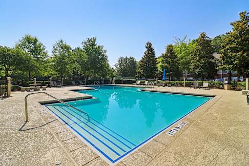 A large outdoor swimming pool surrounded by trees.