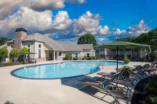 A large swimming pool surrounded by lounge chairs and umbrellas.