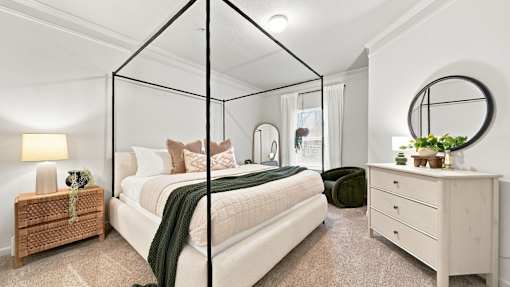 A bedroom with a four poster bed, a nightstand, and a dresser.