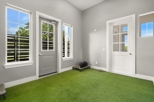 a living room with green astroturf and a door with three windows