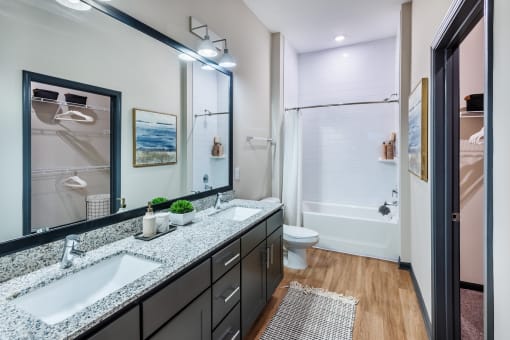 a bathroom with a large mirror and two sinks at The Livano Tryon, Charlotte, 28213