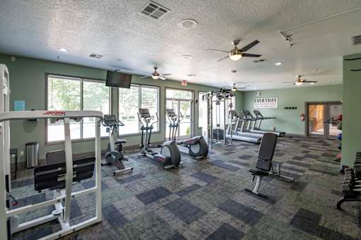 A gym with a variety of equipment including treadmills, weights, and exercise machines.