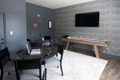 A room with a table, chairs, and a TV mounted on the wall.