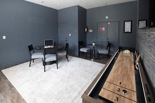 A room with a shuffleboard table and chairs.