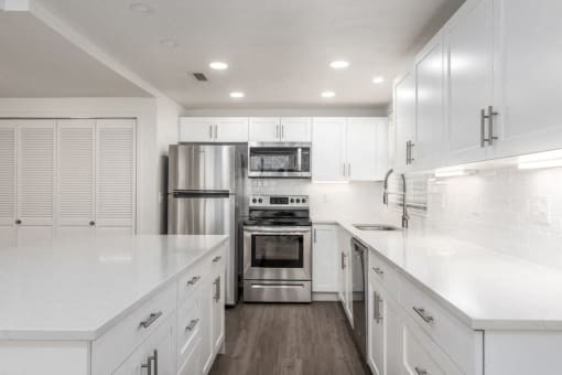 Kitchen with stainless steel appliances, white cabinetry, and quartz countertop