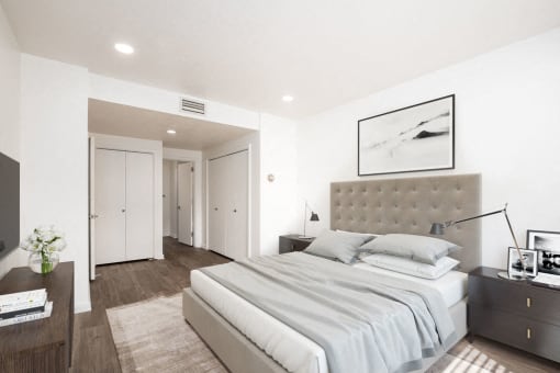 Bedroom with hardwood flooring, white walls, and closets
