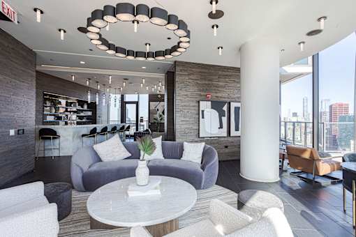 A modern living room with a grey sofa, a white coffee table, and a chandelier.