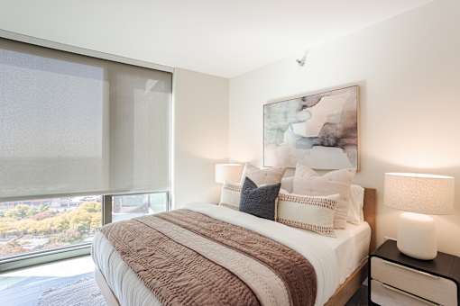 A bedroom with a large bed and a painting on the wall.