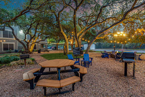A picnic area with tables and chairs under trees.