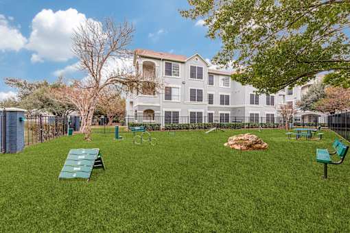 A large grassy area with benches and a building in the background.