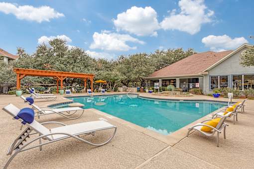 A pool with sun loungers and a building in the background.