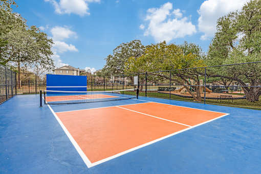 A tennis court with blue and orange colors and a net.