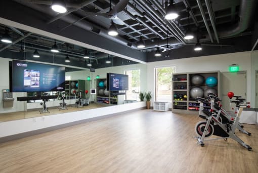 Fitness studio with large mirror along wall with two TVs