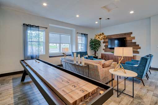 A shiny wooden table is in the middle of a room with a couch and chairs.