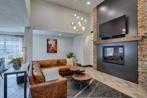 A modern living room with a brown leather couch and a stone fireplace.