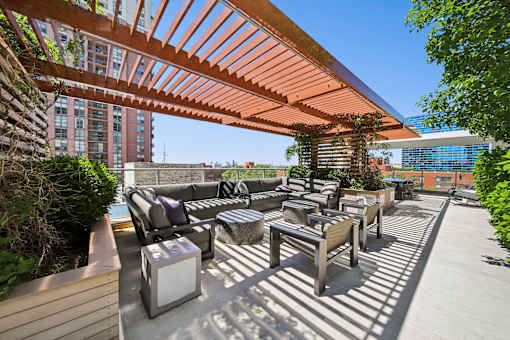 A patio with a wooden pergola and furniture.
