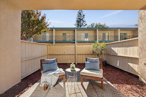 A patio with a table and two chairs with cushions and a blanket.