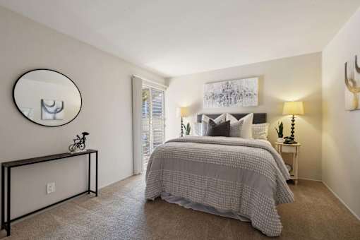 A bedroom with a bed, a mirror, and a painting on the wall.
