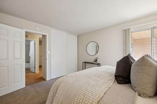 A bedroom with a large bed and a round mirror on the wall.