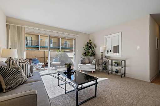 A living room with a couch, a coffee table, and a balcony.