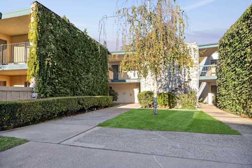 A residential area with a green lawn and a building with a balcony.