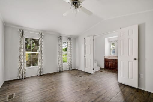 a living room with a ceiling fan and two windows