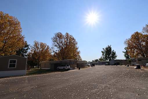 a row of mobile homes in a parking lot with the sun shining over them at Circle Park, Cheyenne, Wyoming