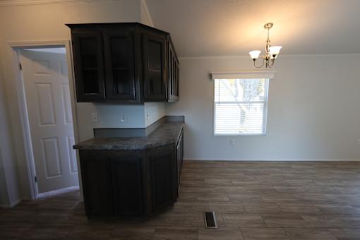 an empty kitchen with dark cabinets and a window at Circle Park, Cheyenne