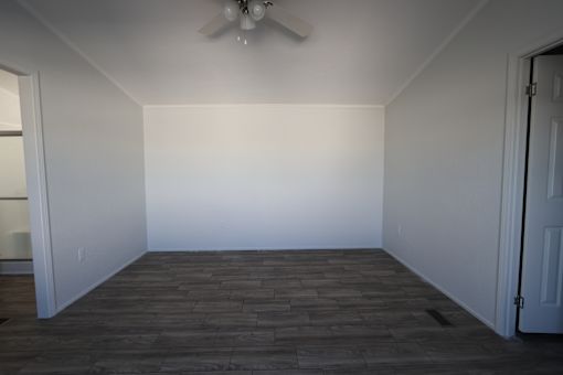 an empty room with a ceiling fan and a white wall at Horizon MHC, Rock Springs, 82901