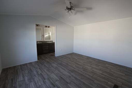 an empty living room with wood flooring and a ceiling fan at Horizon MHC, Rock Springs, WY