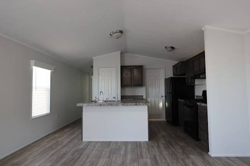 an empty kitchen with a white counter top and a black refrigerator at Horizon MHC, Rock Springs, Wyoming
