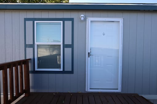 the front door and window of a house with a wooden deck at Horizon MHC, Rock Springs