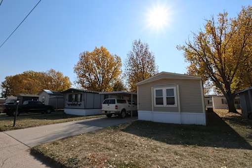 a row of mobile homes on a street with the sun shining over them at Mobile Home Village, Cheyenne, Wyoming