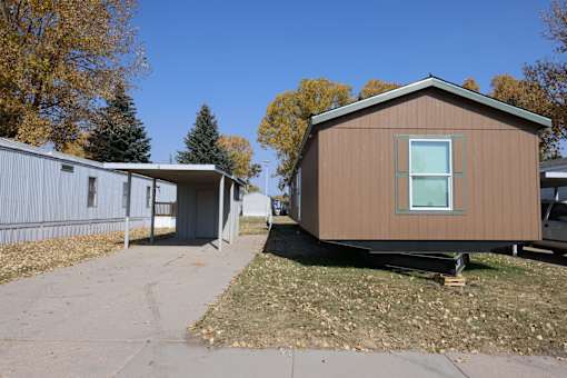 the exterior of a tiny house with a driveway and a shed at Mobile Home Village, Cheyenne, WY, 82001