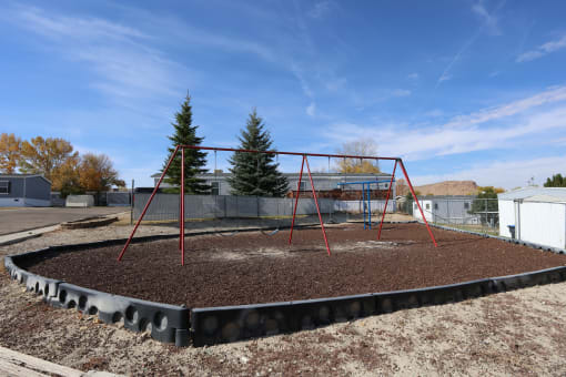 a playground with a swing set and some dirt at Pioneer Park, Green River, 82935