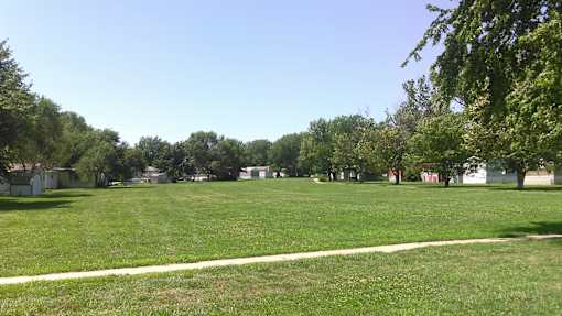 A grassy field with a white line in the middle and trees in the background.