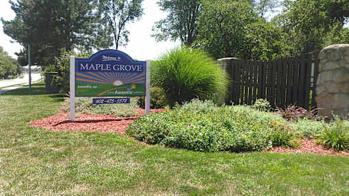 A sign for Maple Grove Assisted Living is shown in front of a fence and some trees.