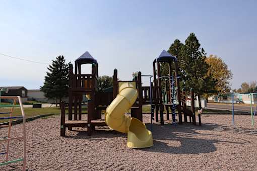 A playground with a yellow slide and wooden structures.