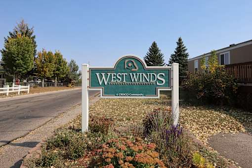 A sign that says West Winds in front of a building.