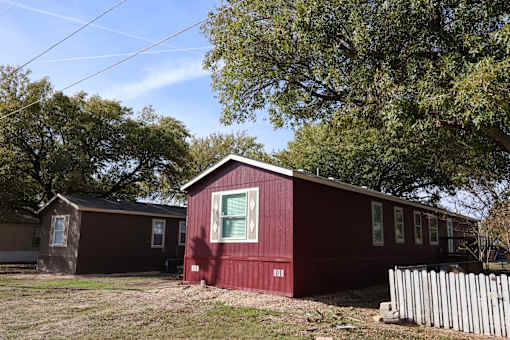 A red house with a white picket fence in front.