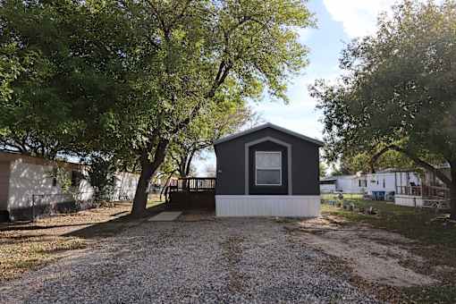 A small black and white house with a gravel driveway in front.