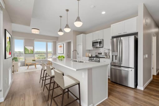 a white kitchen with a large island and stainless steel appliances